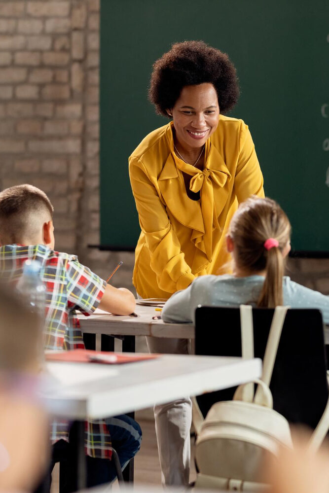 happy-black-elementary-school-teacher-taking-her-students-classroom