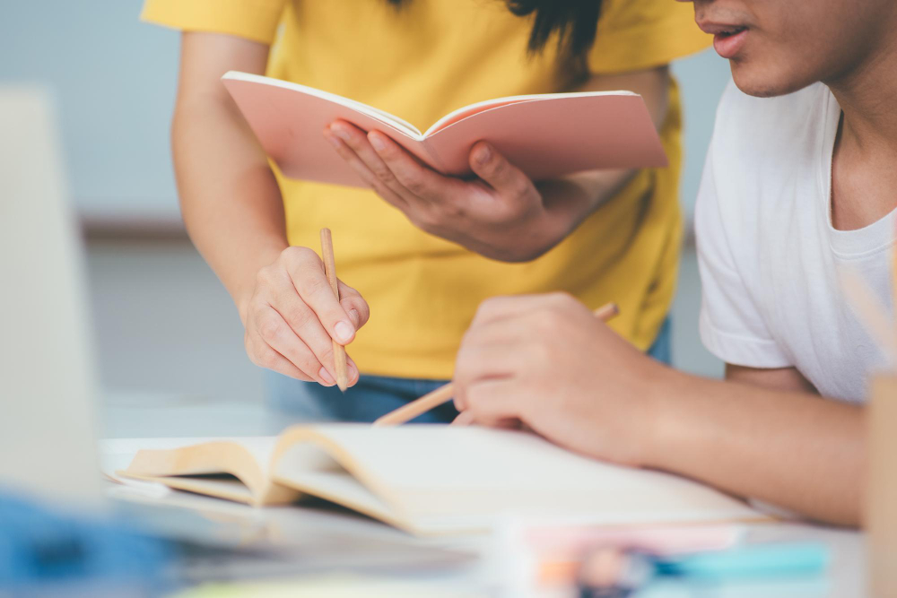 learning-education-school-concept-young-woman-man-studying-test-exam-tutor-books-with-friends-young-students-campus-helps-friend-catching-up-learning